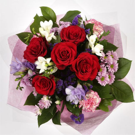 Pastel Beautiful BouquetAn eye-catching hand-tied bouquet including Freesias, Statice, Spray Chrysanthemums and large-headed Red Roses complemented by white & purple Freesias. finished with a cerise ribbon, this vivid selection of flowers will create a st