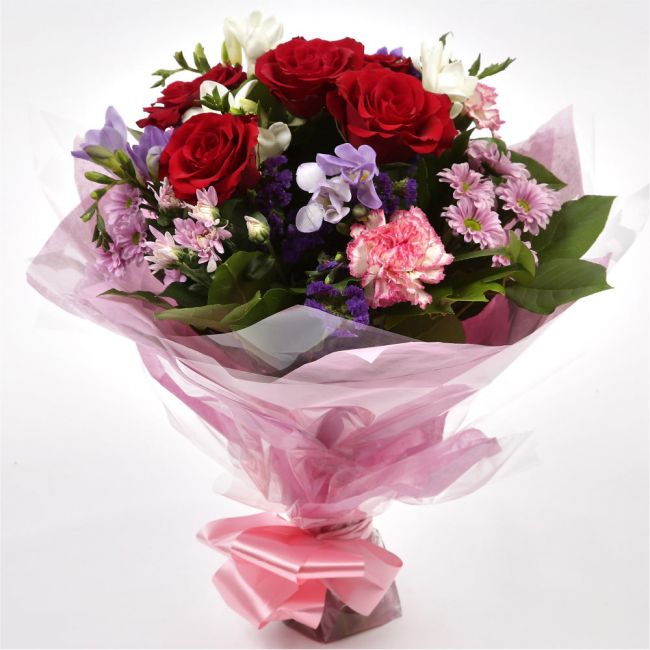 Pastel Beautiful BouquetAn eye-catching hand-tied bouquet including Freesias, Statice, Spray Chrysanthemums and large-headed Red Roses complemented by white & purple Freesias. finished with a cerise ribbon, this vivid selection of flowers will create a st